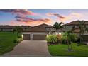 Charming home with a tile roof, a three-car garage, a brick paver driveway, and lush landscaping at 14216 Florida Rosemary Dr, Bradenton, FL 34211