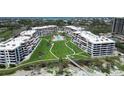 Beautiful aerial view of beachfront condos with a lush green lawn, swimming pool, and scenic surroundings at 1445 Gulf Of Mexico Dr # 203, Longboat Key, FL 34228