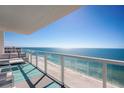 Balcony overlooking the beach with glass railings and lounge furniture at 2425 Gulf Of Mexico Dr # 14B, Longboat Key, FL 34228