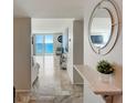Foyer with travertine floors, ocean view, and decorative shelf with round mirror at 2425 Gulf Of Mexico Dr # 14B, Longboat Key, FL 34228