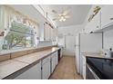 Bright kitchen featuring white cabinets, tile countertops, a large window, and tile flooring at 2820 Greenbriar St, Sarasota, FL 34237