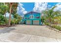 Charming coastal home with vibrant turquoise and purple exterior, balcony, and a two-car garage at 315 Magnolia Ave, Anna Maria, FL 34216