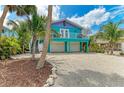 Charming coastal home with vibrant turquoise and purple exterior, balcony, and a two-car garage at 315 Magnolia Ave, Anna Maria, FL 34216