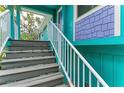 Exterior stairway with white railing, leading up to the main living space of the turquoise beach house at 315 Magnolia Ave, Anna Maria, FL 34216