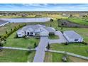 Aerial view of a luxurious home with a large lawn, lake, and a three-car garage at 3574 Recurve Cir, Sarasota, FL 34240