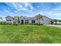 Beautiful white home with a well-manicured lawn, palm trees, and an attached three-car garage at 3574 Recurve Cir, Sarasota, FL 34240