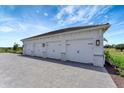 A detached three-car garage with white doors and stone accents on a paved driveway at 3574 Recurve Cir, Sarasota, FL 34240