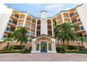 Elegant condo building featuring a grand entrance, lush landscaping, and palm trees at 5450 Eagles Point Cir # 404, Sarasota, FL 34231