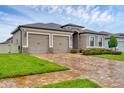 Lovely tan home with a two-car garage, stone accents, and a brick paver driveway, complemented by a vibrant green lawn at 6636 35Th E Ct, Sarasota, FL 34243