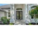 Close-up of the front entrance showcasing the double doors, columns, arched window, and manicured landscaping at 6641 Saint James Xing, University Park, FL 34201