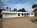 Charming single-story home featuring white paint, a two-car garage, and tropical landscaping with palm trees at 782 Birdsong Ln, Sarasota, FL 34242