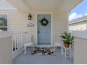 Detailed view of the light blue front door with wreath and matching wicker chairs for welcoming charm at 12682 Shimmering Oak Cir, Venice, FL 34293