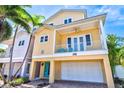 Charming yellow two-story home with balcony, turquoise door, brick driveway, and palm trees at 145 50Th St, Holmes Beach, FL 34217