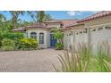 Beautiful exterior with a brick driveway, barrel tile roof, lush landscaping and three-car garage at 1864 Goldenrod St, Sarasota, FL 34239