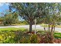 Landscaped front yard featuring mature shade trees and colorful flower beds at 2662 6Th E Ct, Ellenton, FL 34222