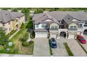 Aerial view of a tan and white townhome featuring a two-car garage and brick paved driveway at 30073 Southwell Ln, Wesley Chapel, FL 33543