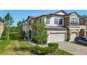 Townhome featuring manicured lawn and landscaping, covered entryway and two-car garage at 30073 Southwell Ln, Wesley Chapel, FL 33543