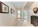 Bright hallway with light wood floors, wall decor, and a view to the living area, creating an open flow at 3129 61St E Ter, Ellenton, FL 34222