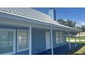 Charming blue home with metal roof, front porch and blue deck under a sunny blue sky at 3320 19Th Street E Ct, Bradenton, FL 34208
