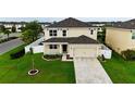 Two-story home with a two-car garage, surrounded by lush greenery and a white picket fence at 4005 Willow Branch Pl, Palmetto, FL 34221