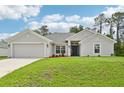 Charming single-story home with a well-manicured lawn and a two-car garage, under a blue sky at 4610 Clarke St, North Port, FL 34286
