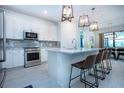 Stylish kitchen boasting white cabinetry, stainless steel appliances, a spacious island, and pendant lighting at 6714 Alstead Cir, Bradenton, FL 34202