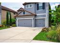 Charming two-story home featuring a gray stucco exterior, red tile roof, and meticulously landscaped front yard at 7020 Island Queen Ct, Sarasota, FL 34233