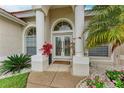 Close-up of the front entrance with decorative columns, a double glass door, and manicured flowerbeds at 7327 38Th Court East, Sarasota, FL 34243