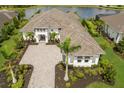 Aerial view of a beautiful home with a stone driveway, three-car garage, and professional landscaping near the water at 8218 Genoa Blvd, Lakewood Ranch, FL 34202