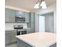Modern kitchen with gray cabinets, stainless steel appliances, white countertops, and a center island at 115 41St Ne Ave, St Petersburg, FL 33703