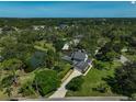 Aerial view showcasing the house and surrounding lush greenery, including a pond, and a long driveway at 13514 4Th E Plz, Bradenton, FL 34212