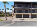 The exterior of a two-story condo building featuring car parking garages on the ground floor with staircase access to upper-level condos at 2729 North Beach Rd # 212, Englewood, FL 34223