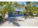 Charming blue exterior with gravel yard and tropical plants providing shade at 3016 Gulf Dr, Holmes Beach, FL 34217