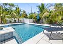 Inviting backyard pool surrounded by lush tropical landscaping, a white fence, and lounge chairs at 3016 Gulf Dr, Holmes Beach, FL 34217