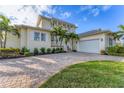 Beautiful two-story home with a two-car garage, tropical landscaping, and a brick driveway at 634 Key Royale Dr, Holmes Beach, FL 34217