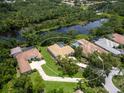 Aerial view of home near a pond; property has a screened-in pool and is surrounded by greenery at 7003 Lancaster Ct, University Park, FL 34201
