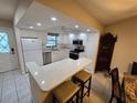 Bright kitchen featuring white cabinets, updated appliances, and a breakfast bar at 1211 Capri Isles Blvd # 116, Venice, FL 34292