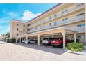 Exterior shot of a condo building featuring convenient covered parking with brick pavers and well-maintained landscaping at 1250 N Portofino Dr # 208, Sarasota, FL 34242