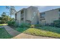 Side view of condo building featuring muted exterior, sidewalks, and vibrant green lawn with lush landscaping at 137 Woodland Pl, Osprey, FL 34229