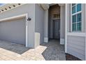Front entrance and a gray brick driveway leading to the garage door at 17632 Santorini Ct, Venice, FL 34293