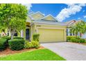 Inviting yellow home with a green door, brick driveway, and lush landscaping for enhanced curb appeal at 2085 Mattamy Ct, Venice, FL 34292