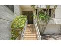 Condo entrance with tiled stairs, lush landscaping, and a secure door at 222 Beach Rd # 7, Sarasota, FL 34242