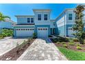 Inviting exterior view of light blue townhouses with brick paver driveways and lush landscaping at 317 Via Tuscany Ave, Sarasota, FL 34243