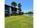 Picturesque backyard view with lush green lawn, a tranquil lake, and mature palm trees under a blue sky at 3500 El Conquistador Pkwy # 347, Bradenton, FL 34210