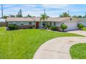 Well-kept single-story home featuring a lush green lawn and a circular driveway at 3621 S Lockwood Ridge Rd, Sarasota, FL 34239