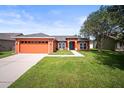 Well maintained single Gathering home with a 2 car garage, manicured lawn, and vibrant orange exterior at 4194 Banbury Cir, Parrish, FL 34219