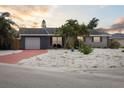 Inviting single-story home with a colorful red driveway and rock landscaping, captured at twilight at 4303 83Rd W St, Bradenton, FL 34209