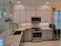 Modern kitchen featuring granite counters, stainless steel appliances and sleek white cabinets at 5219 Barnett Cir, Bradenton, FL 34211