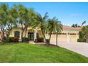 Inviting home featuring a tile roof, a well-manicured lawn, palm trees, and a three-car garage at 6811 Honeysuckle Trl, Lakewood Ranch, FL 34202