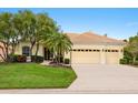 Charming home featuring a tile roof, a well-manicured lawn, palm trees, and a three-car garage at 6811 Honeysuckle Trl, Lakewood Ranch, FL 34202